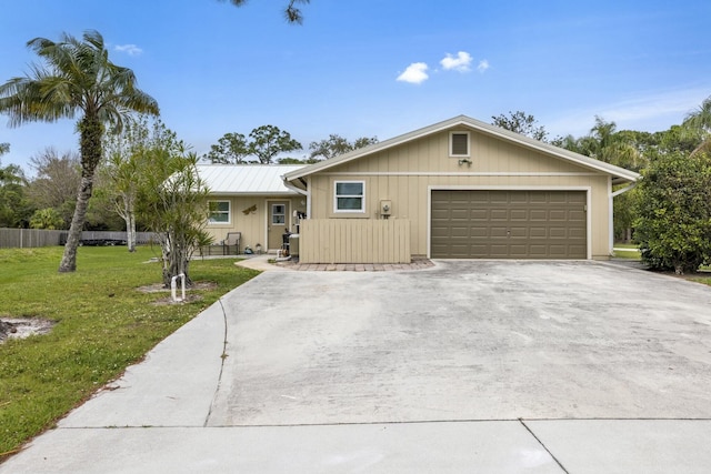 single story home featuring a garage, metal roof, driveway, and a front lawn