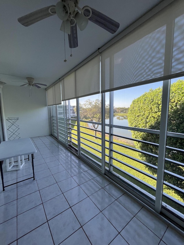 unfurnished sunroom featuring a water view and ceiling fan