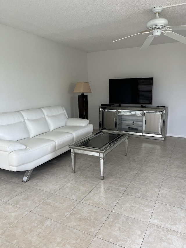 living room featuring light tile patterned flooring, ceiling fan, and a textured ceiling