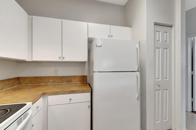 kitchen with freestanding refrigerator, light countertops, and white cabinetry