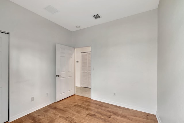 unfurnished room with baseboards, light wood finished floors, and visible vents