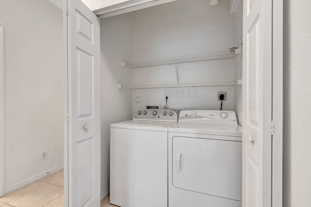 laundry room with baseboards, light tile patterned floors, laundry area, and washer and dryer