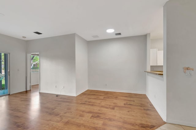 spare room featuring visible vents, baseboards, and light wood-type flooring