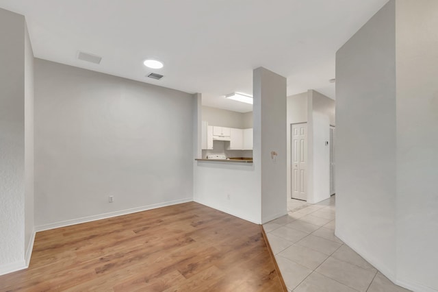 unfurnished living room featuring baseboards, visible vents, and light wood-style floors