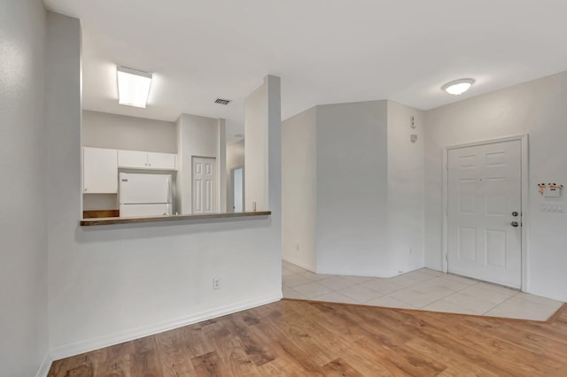 unfurnished room featuring baseboards, light wood finished floors, and visible vents