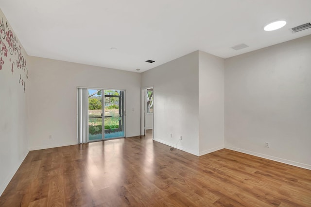 unfurnished room with baseboards, visible vents, and wood finished floors