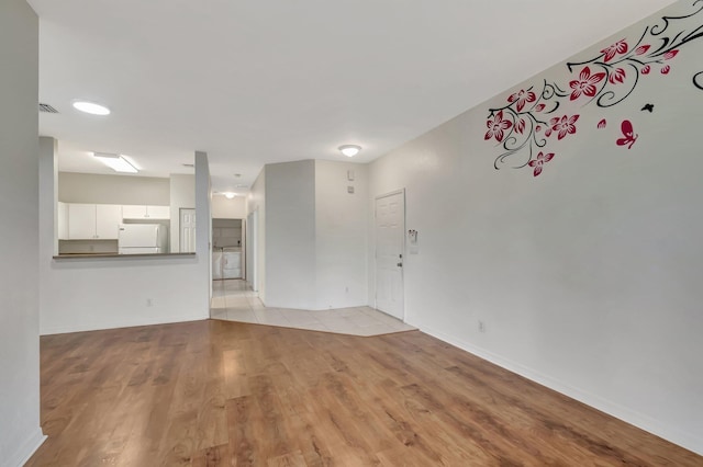 unfurnished living room with baseboards, visible vents, and light wood finished floors