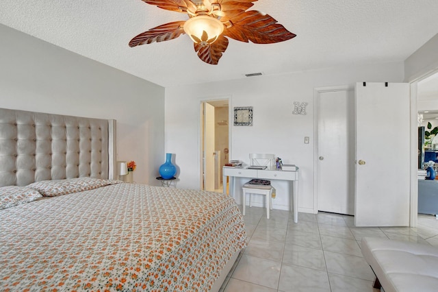 bedroom featuring light tile patterned floors, visible vents, a ceiling fan, and a textured ceiling