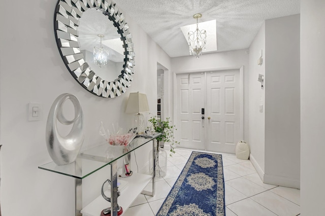 foyer entrance with a notable chandelier, a textured ceiling, baseboards, and light tile patterned floors