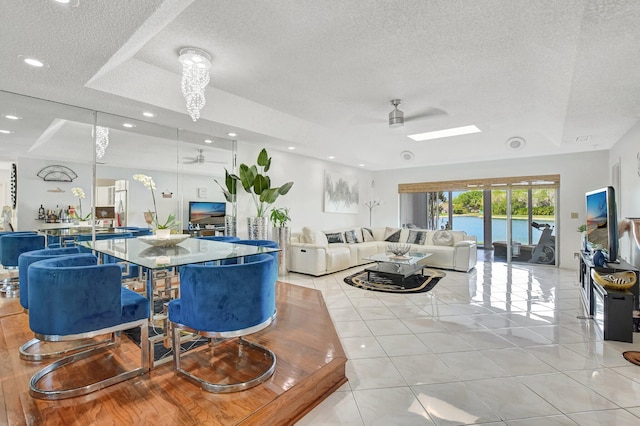 dining room featuring light tile patterned floors, a textured ceiling, a raised ceiling, and a ceiling fan