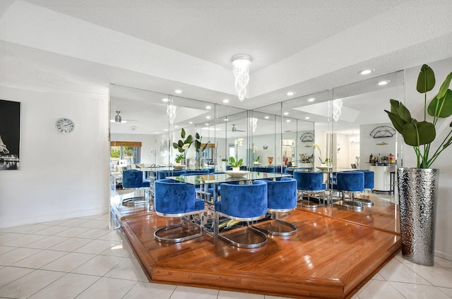 dining area featuring a textured ceiling, light tile patterned flooring, recessed lighting, baseboards, and a tray ceiling