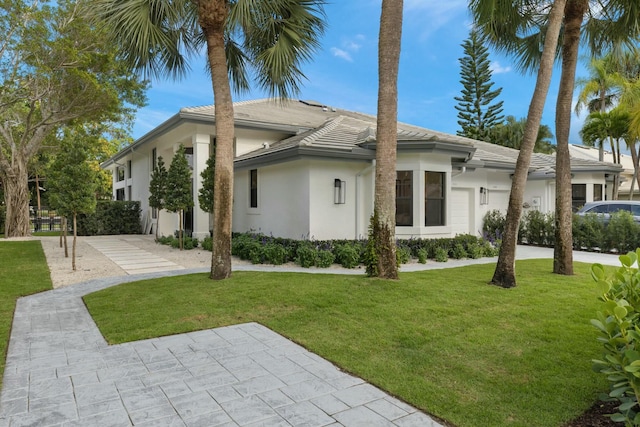 view of side of home with an attached garage, a lawn, and stucco siding