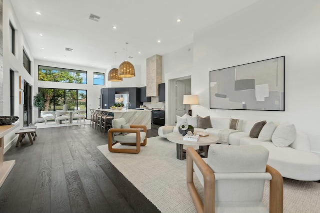 living area featuring visible vents, wood finished floors, a towering ceiling, and recessed lighting