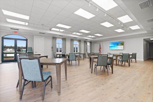 dining space with light hardwood / wood-style floors, a paneled ceiling, and a raised ceiling