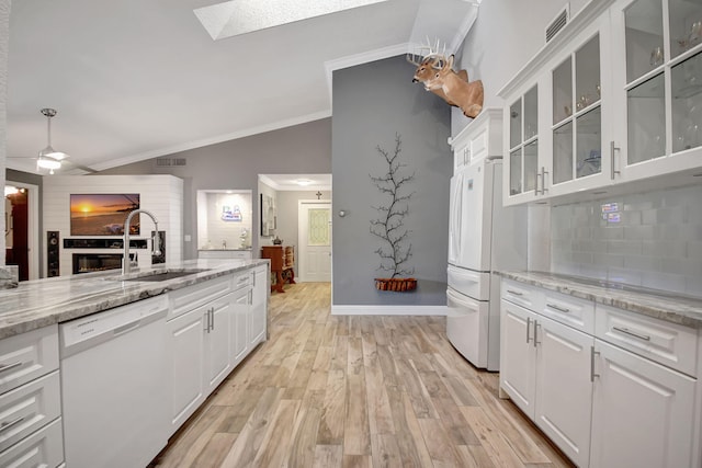 kitchen featuring white appliances, a sink, white cabinetry, and light stone countertops