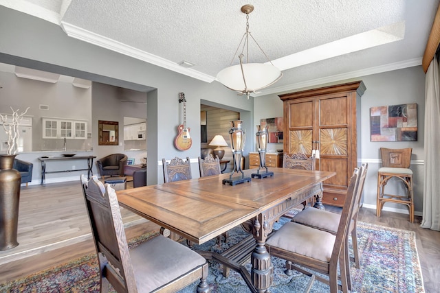 dining space with a textured ceiling, light wood-type flooring, and crown molding