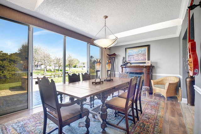 dining room with ornamental molding, a textured ceiling, baseboards, and wood finished floors