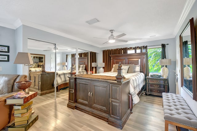 bedroom featuring light wood-style floors, visible vents, ornamental molding, and a ceiling fan