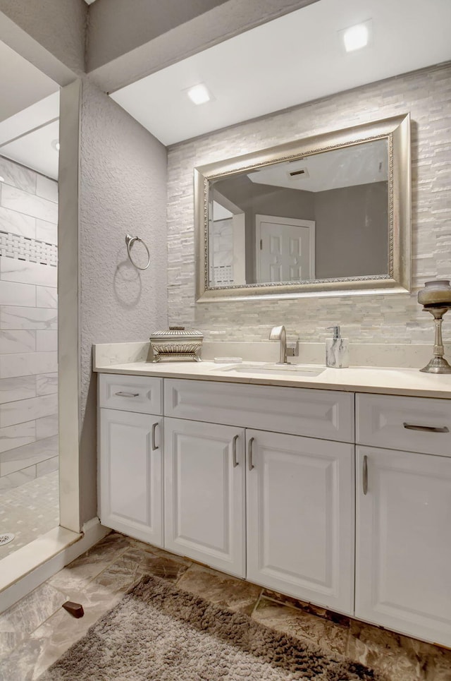 bathroom featuring backsplash, a textured wall, a shower stall, and vanity