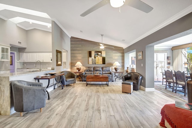 living area featuring wooden walls, an accent wall, crown molding, and light wood-style flooring