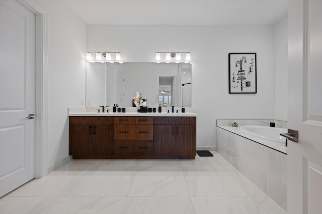 full bath with double vanity, marble finish floor, a sink, and a garden tub