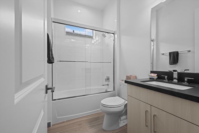 bathroom with toilet, vanity, combined bath / shower with glass door, and wood finished floors