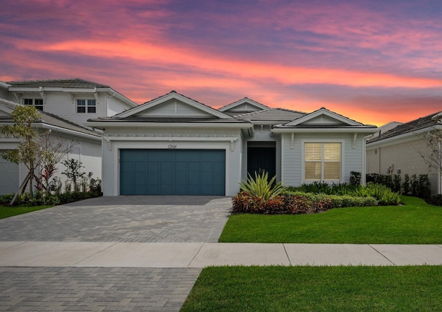 view of front of house with an attached garage, decorative driveway, and a yard