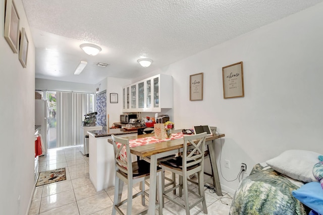 tiled dining space with a textured ceiling