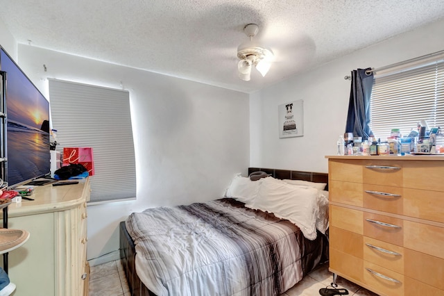 bedroom featuring ceiling fan, light tile patterned floors, and a textured ceiling