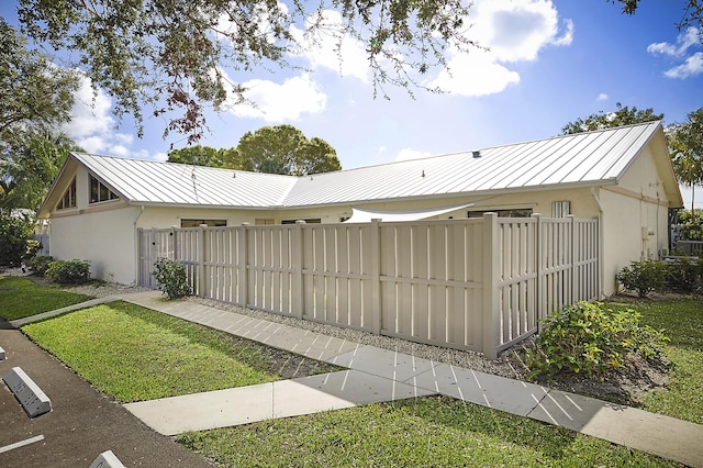 view of front facade featuring a standing seam roof, fence, metal roof, and stucco siding