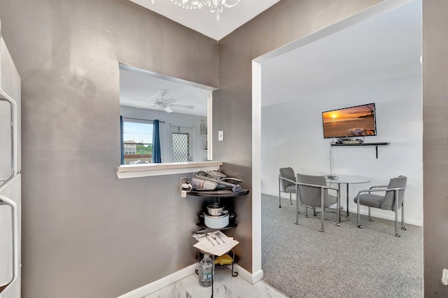 carpeted foyer featuring a ceiling fan and baseboards