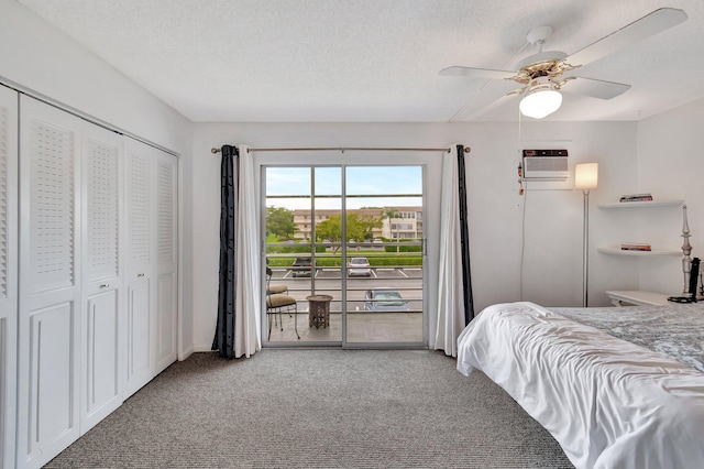 carpeted bedroom featuring a ceiling fan, access to outside, a textured ceiling, a closet, and a wall mounted AC