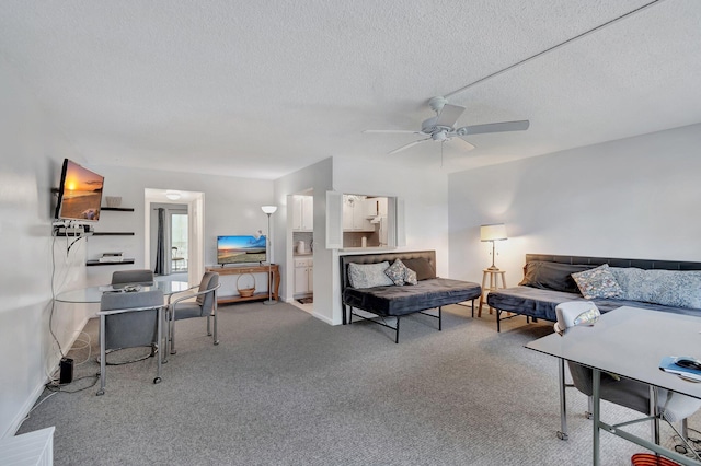 carpeted living room with a ceiling fan, a textured ceiling, and baseboards