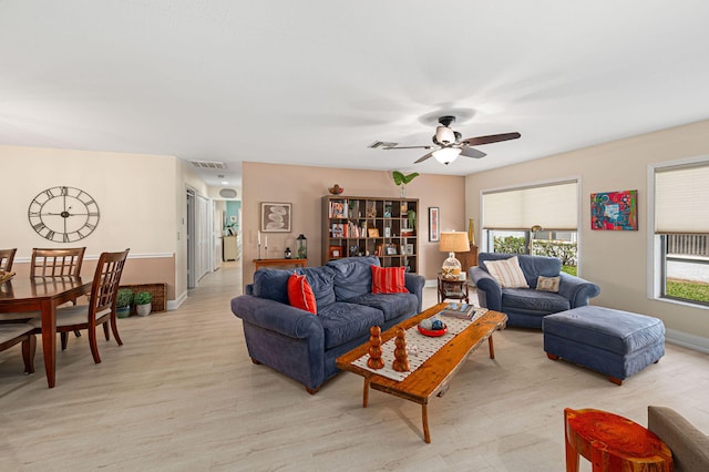 living area featuring light wood-style floors, baseboards, visible vents, and a ceiling fan