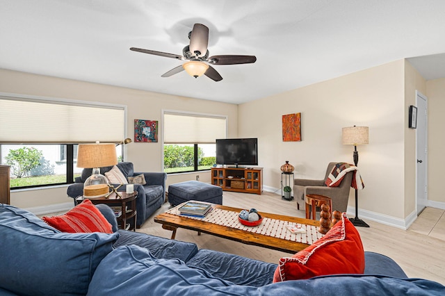 living room featuring baseboards, a healthy amount of sunlight, ceiling fan, and light wood finished floors