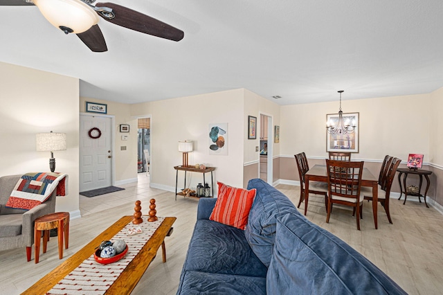 living room featuring ceiling fan with notable chandelier, light wood-type flooring, visible vents, and baseboards