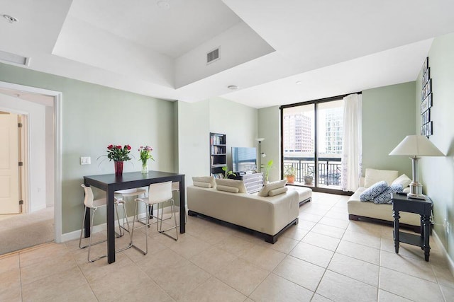 living room with light tile patterned floors and a raised ceiling