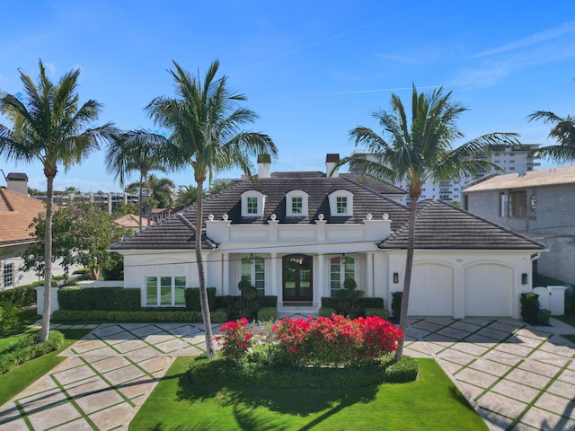 view of front of property with a tile roof, a chimney, an attached garage, and stucco siding