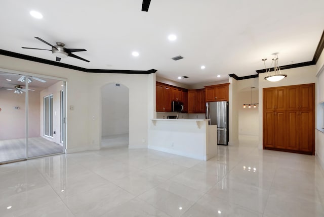 kitchen featuring arched walkways, pendant lighting, light countertops, appliances with stainless steel finishes, and open floor plan