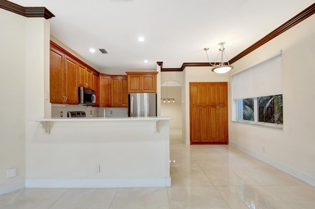 kitchen featuring brown cabinets, stainless steel appliances, light countertops, hanging light fixtures, and a peninsula