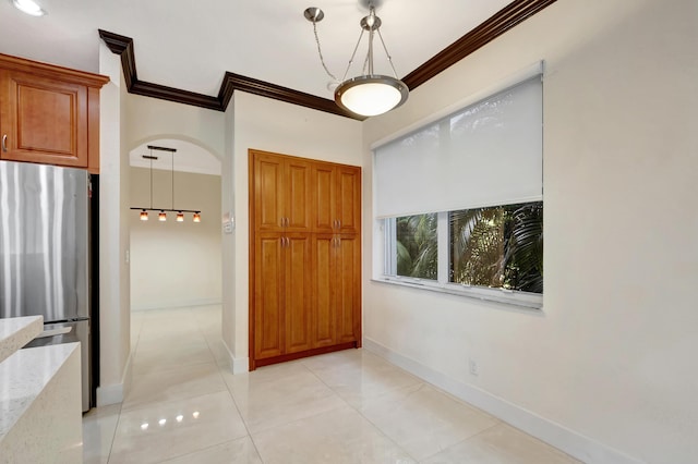 interior space featuring light tile patterned floors, baseboards, arched walkways, and crown molding