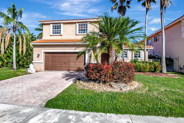 mediterranean / spanish home with a garage, a tile roof, decorative driveway, stucco siding, and a front lawn