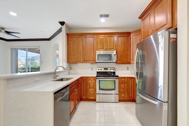 kitchen with light countertops, appliances with stainless steel finishes, a sink, and brown cabinets