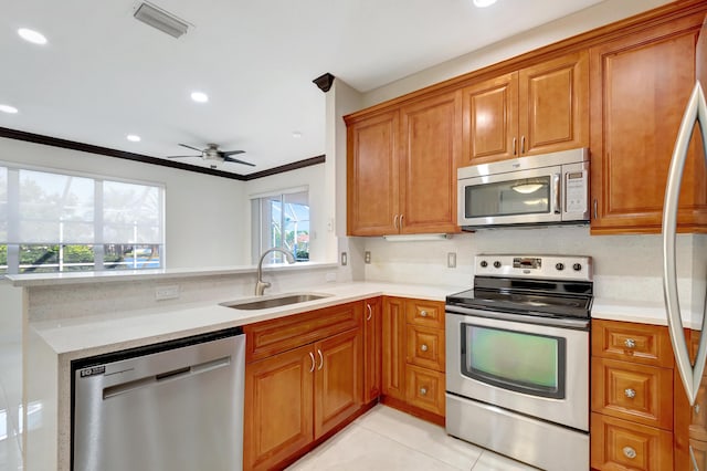 kitchen with brown cabinets, stainless steel appliances, a sink, and light countertops