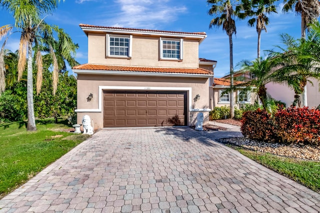 mediterranean / spanish-style home featuring a garage, decorative driveway, a tile roof, and stucco siding