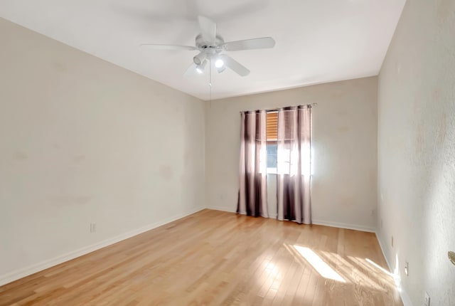 spare room with ceiling fan, light wood finished floors, and baseboards