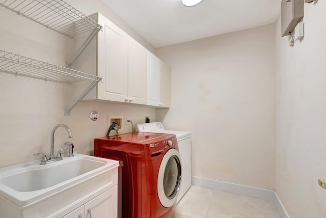 laundry area with light tile patterned floors, cabinet space, a sink, separate washer and dryer, and baseboards