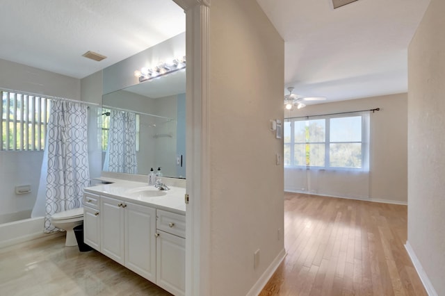 bathroom featuring visible vents, toilet, shower / bath combo, vanity, and baseboards