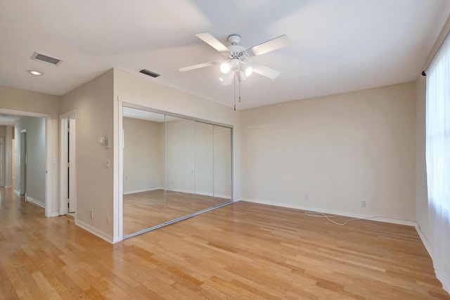 unfurnished bedroom featuring light wood-style floors, baseboards, visible vents, and a closet