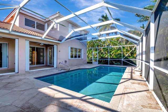 pool featuring glass enclosure, ceiling fan, and a patio area